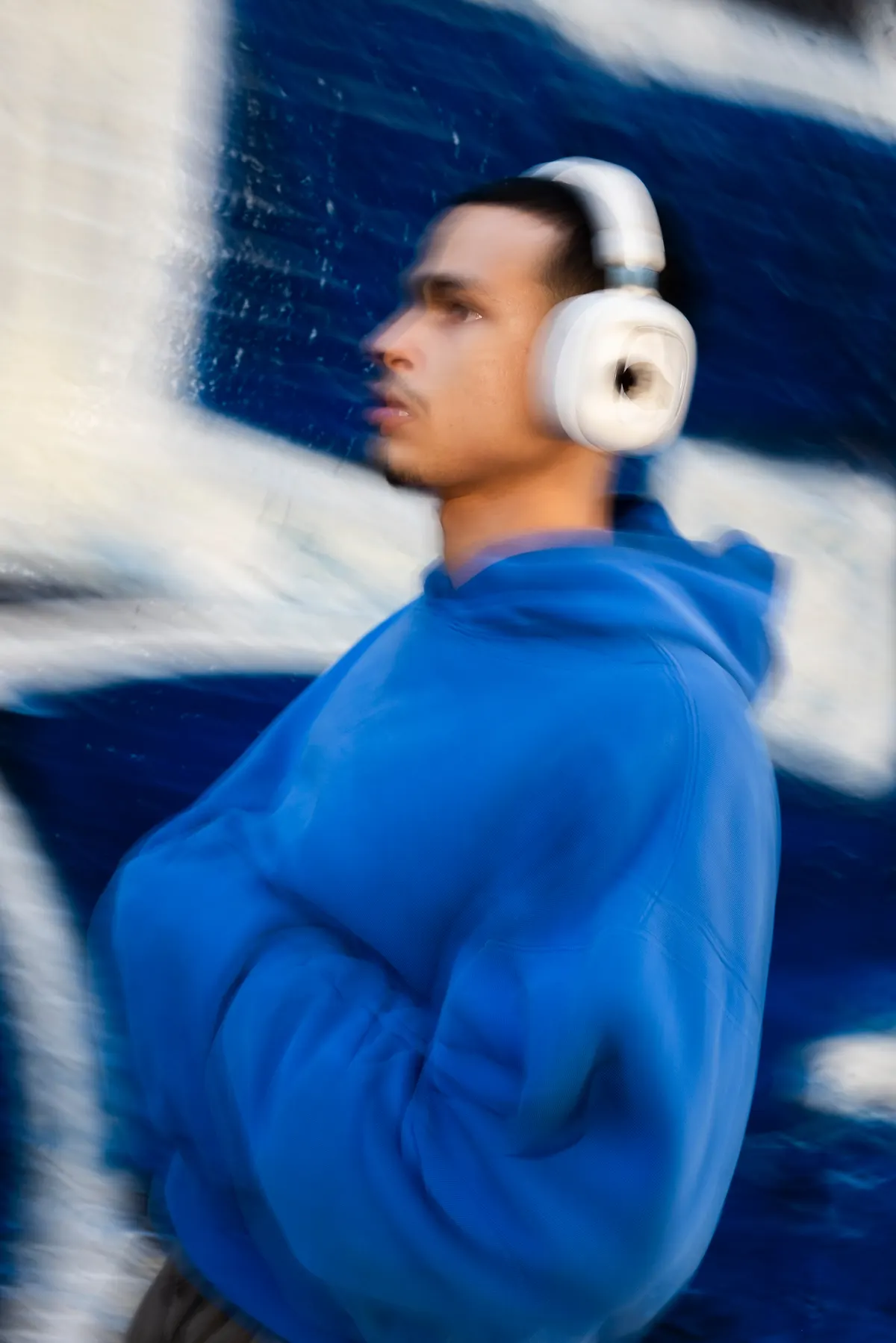 Person wearing white Volta Audio headphones, motion blur against a painted wall