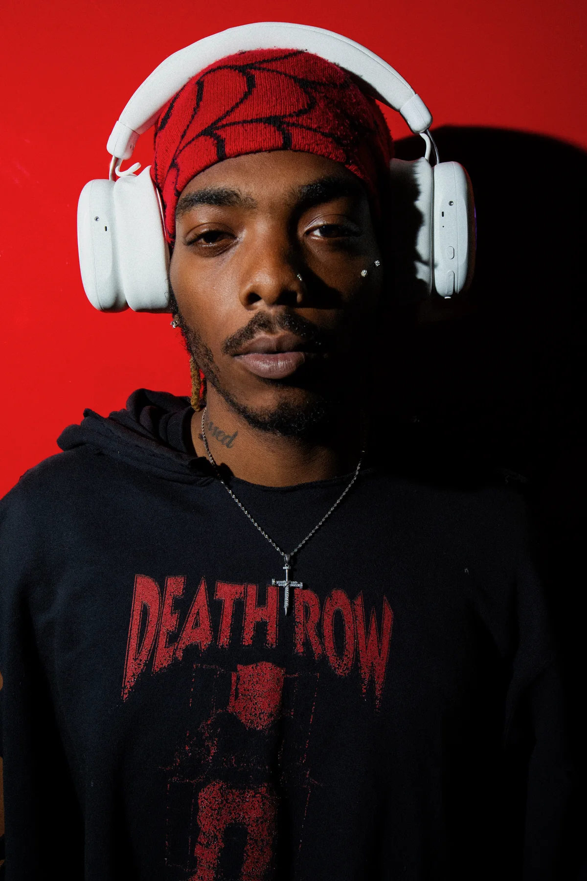 Person in a red beanie wearing white Volta Audio headphones against a red wall