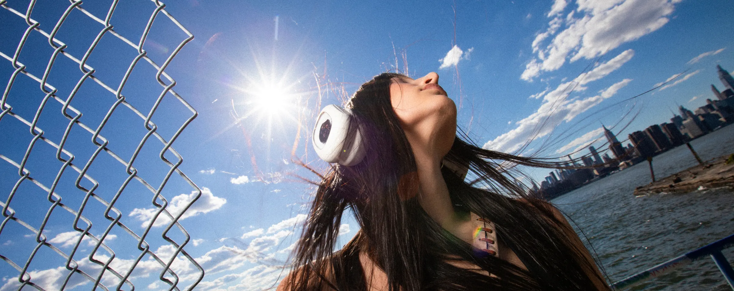Person wearing white Volta Audio headphones by the New York City waterfront
